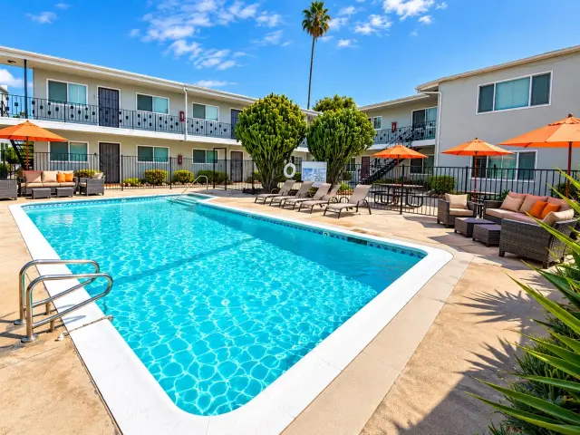 Swimming pool and courtyard with orange umbrellas and lounge seating