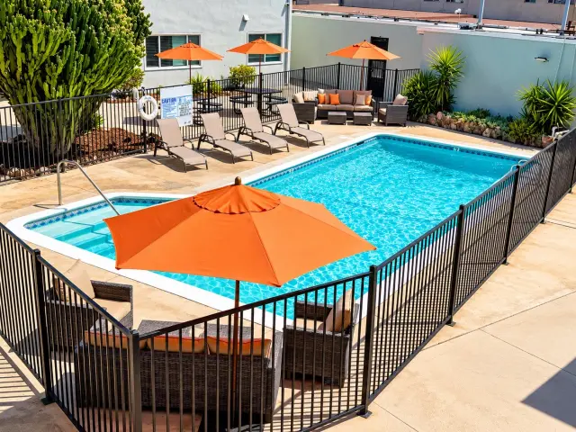 Fenced swimming pool with an orange umbrella, seen from above