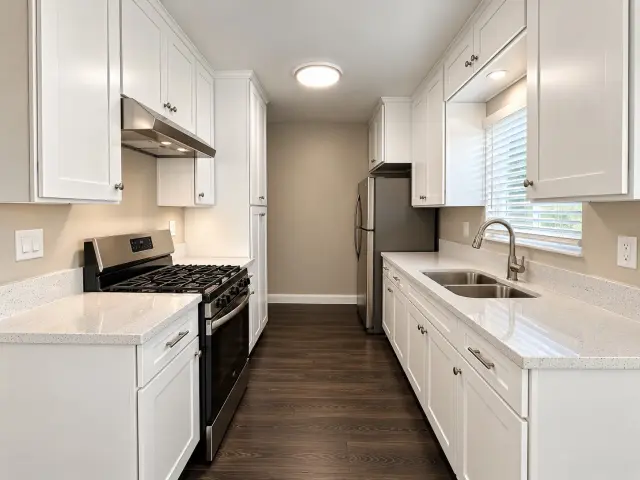 Kitchen with white cabinets, a gas range and a stainless steel refrigerator
