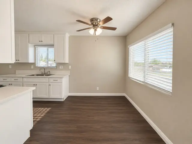 Living area open to the kitchen, with a ceiling fan and wood-style flooring