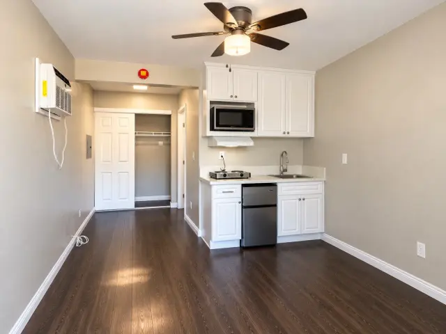 Room with a kitchenette, a ceiling fan and a wall-mounted heating and cooling unit