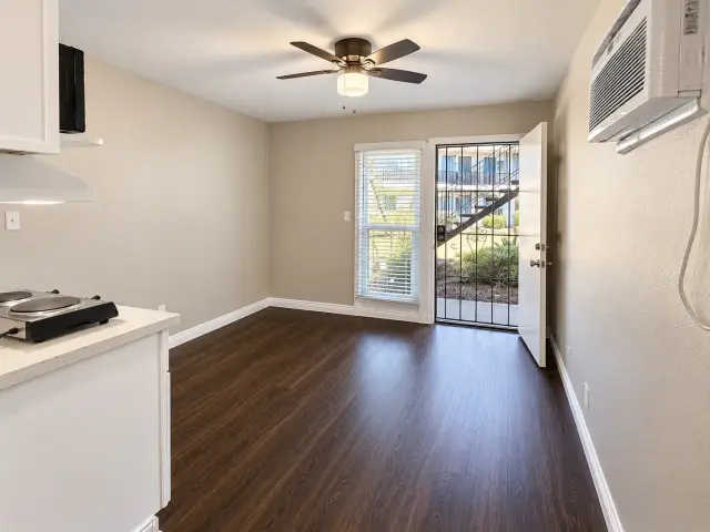 Room with a ceiling fan, a wall-mounted heating and cooling unit and a security screen door