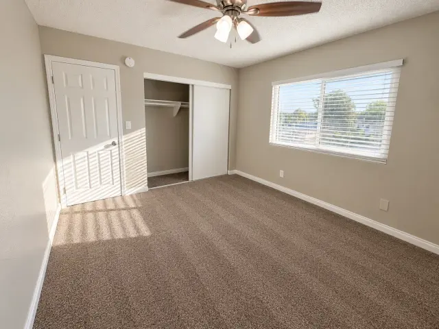 Carpeted bedroom with a ceiling fan and a closet