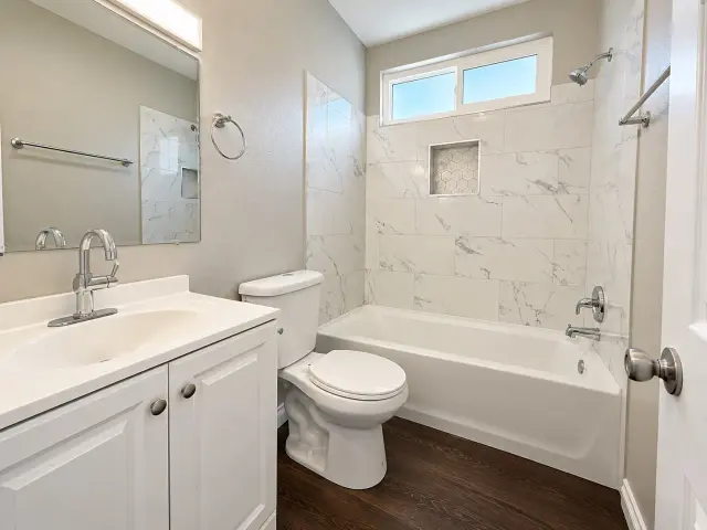 Bathroom with a tub, marble-look tile and a white vanity